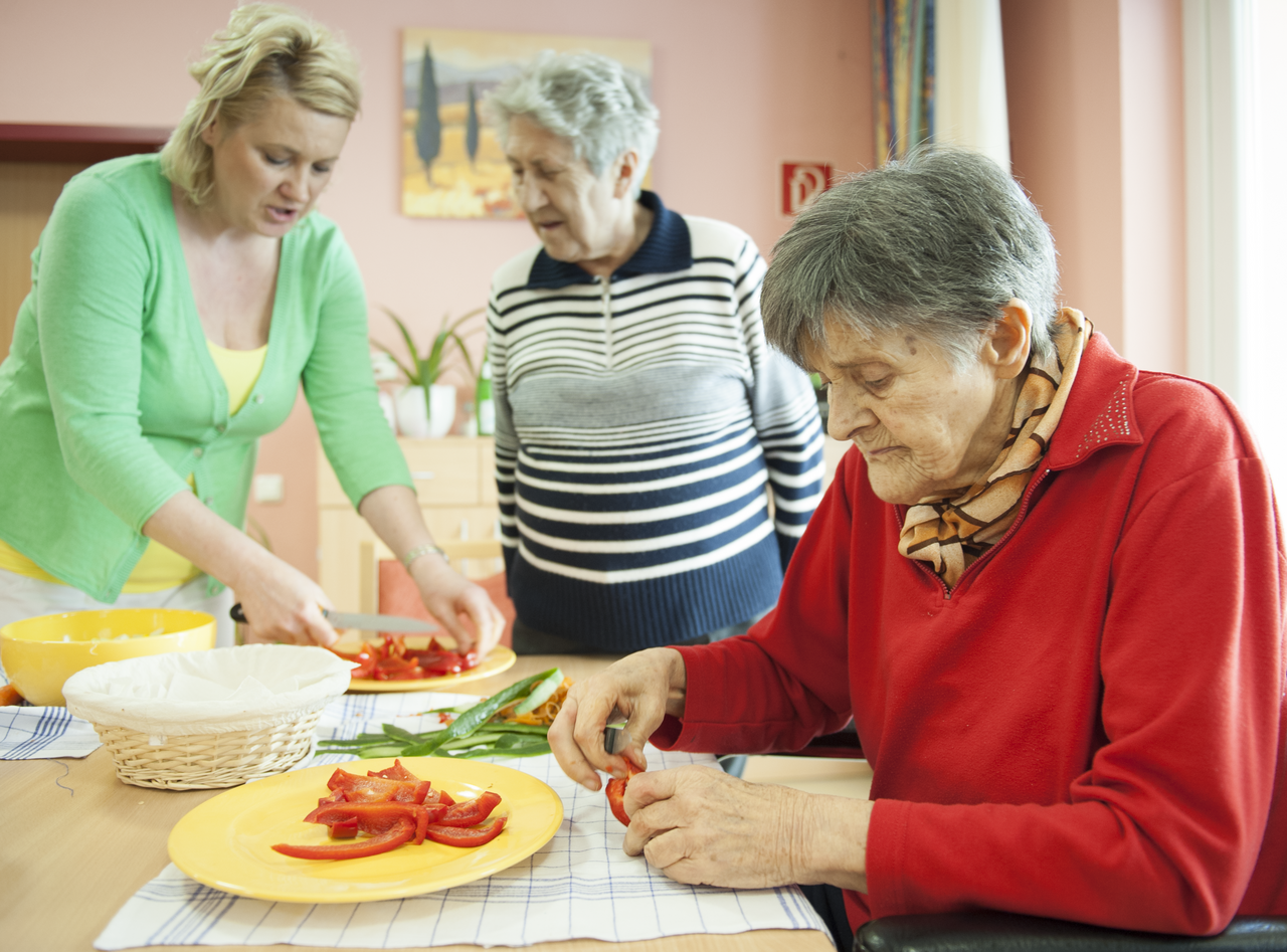 Senioren kochen gemeinsam mit einer Pflegekraft