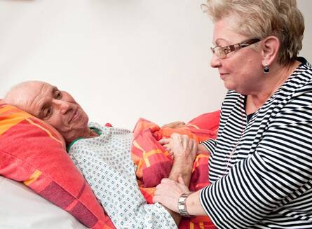 Gut versorgt und medizinisch betreut am Lebensende Frau am Bett eines Schwerstkranken
